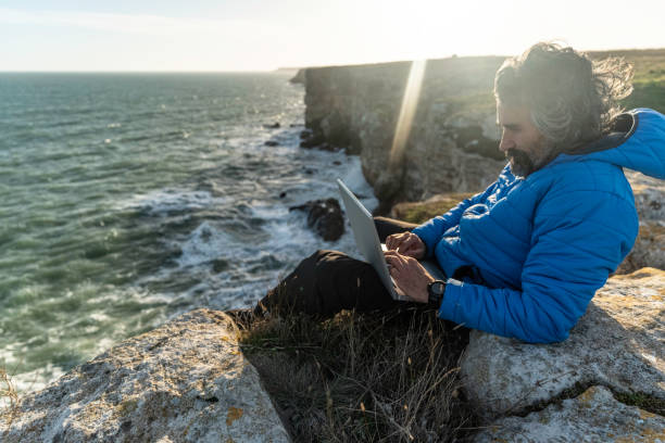 istock People and nature. Man works on laptop at seaside. copy space 1551922912
