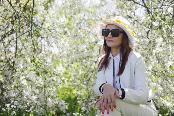 istock A woman poses against the backdrop of white flowering trees. 1551928781