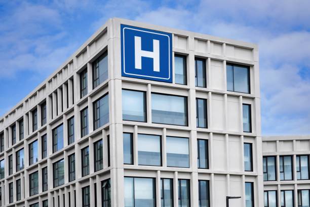 istock Modern concrete building with large blue H sign for hospital 1551933711