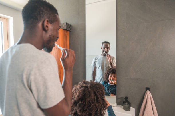 istock Black-American Mid Adult Father and Son Brushing Teeth Together 1551948074