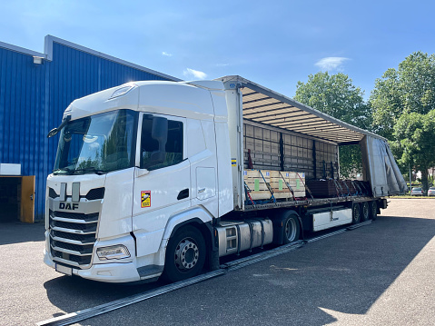 France - 06.23.2023: Cargo transportation of screws in wooden and metal boxes in a semi-trailer of a daf xf truck. Side loading of bolts.