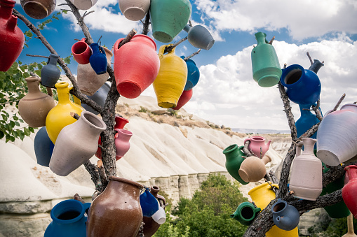 Colorful ceramic vases hanging on tree branch on mountain background in Turkey