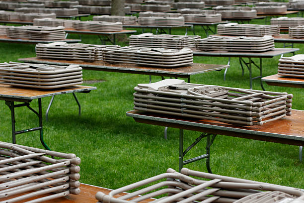 Tables and Chairs neatly stacked on a lawn at Harvard Yard, waiting for people to use them at an event.