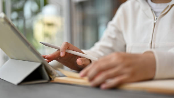 istock Close-up image of an Asian female using her digital tablet while siting in a coffee shop. remote working 1552171627