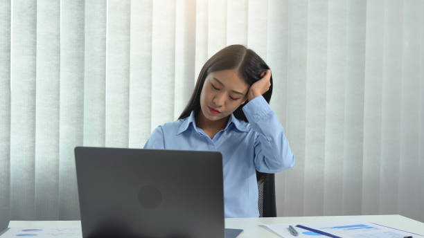 istock Asian woman sitting and working has a headache. 1552183111
