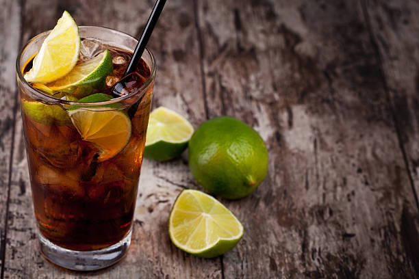 Cuba Libre drink placed on rustic table Cuba Libre Drink with lime on a wooden table cuba libre stock pictures, royalty-free photos & images