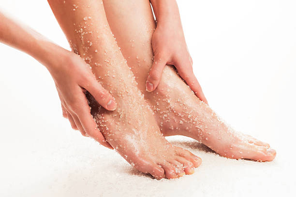 Feet treatment Beauty treatment for legs. Hand masagging feet with sea salt. Studio shot. scrubs stock pictures, royalty-free photos & images