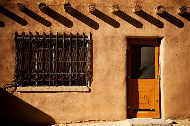 Pueblo home at Acoma with orange door and barred window.