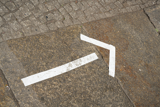 white marker made of tape on a footpath in the city center of Berlin as a signpost to an event