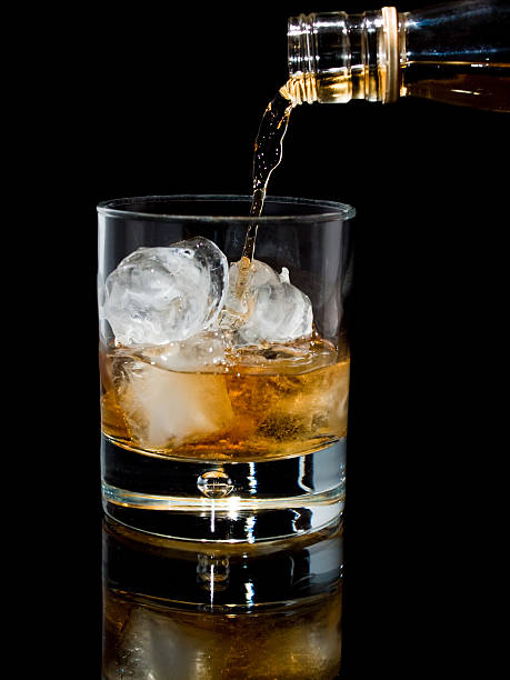 istock Pouring whisky with ice on black background 155227124