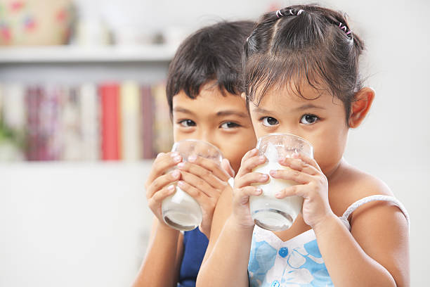 dois rapaz e rapariga beber leite - milk child drinking little girls imagens e fotografias de stock