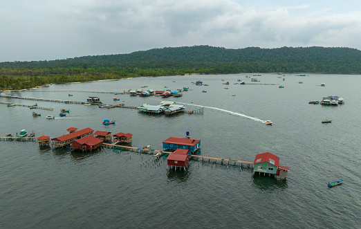 Tatagan Semporna, Malaysia-Nov 20,2021: Wooden houses and boats at the Sea Bajau water village, set against the backdrop of hilltops formed from sandstone and sedimentary rock