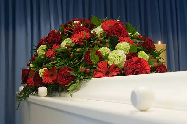 A white coffin in a mortuary with a flower arrangement
