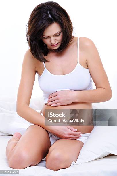 Pregnant Woman Sitting On Bed And Stroking Her Tummy Stock Photo - Download Image Now