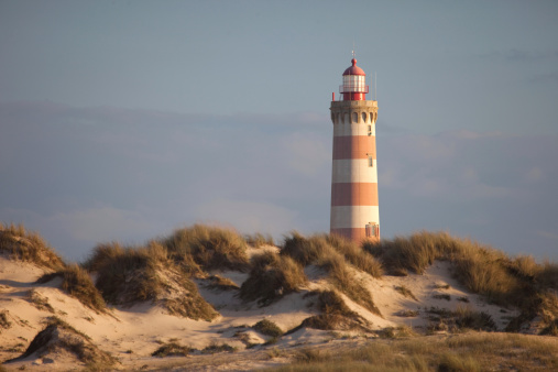 Near from a dune, this lighthouse helps the sailors.