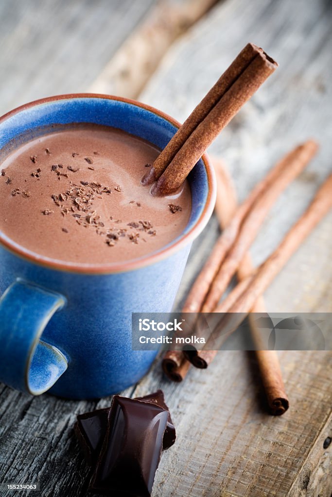 Mug of hot chocolate with cinnamon sticks Hot chocolate with cinnamon stick in blue cup Beige Stock Photo