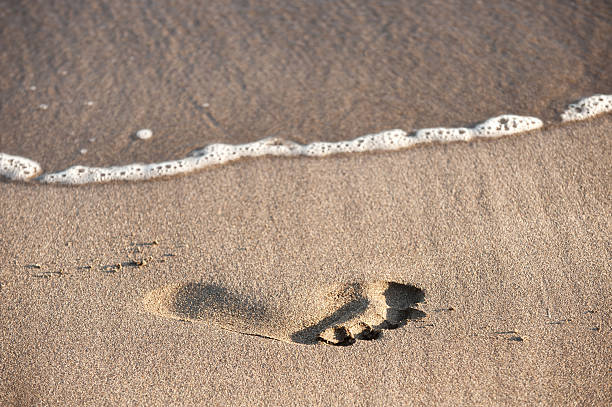 Wave Approaching Footprint in Sand stock photo