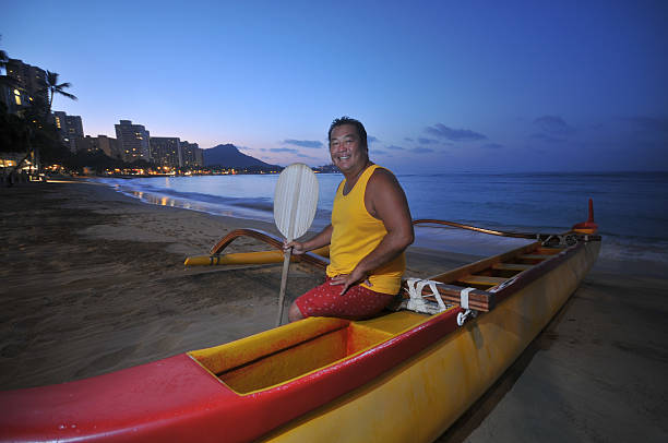 Beach boy in an outrigger canoe Beach boy sits in an outrigger canoe on the beach outrigger stock pictures, royalty-free photos & images