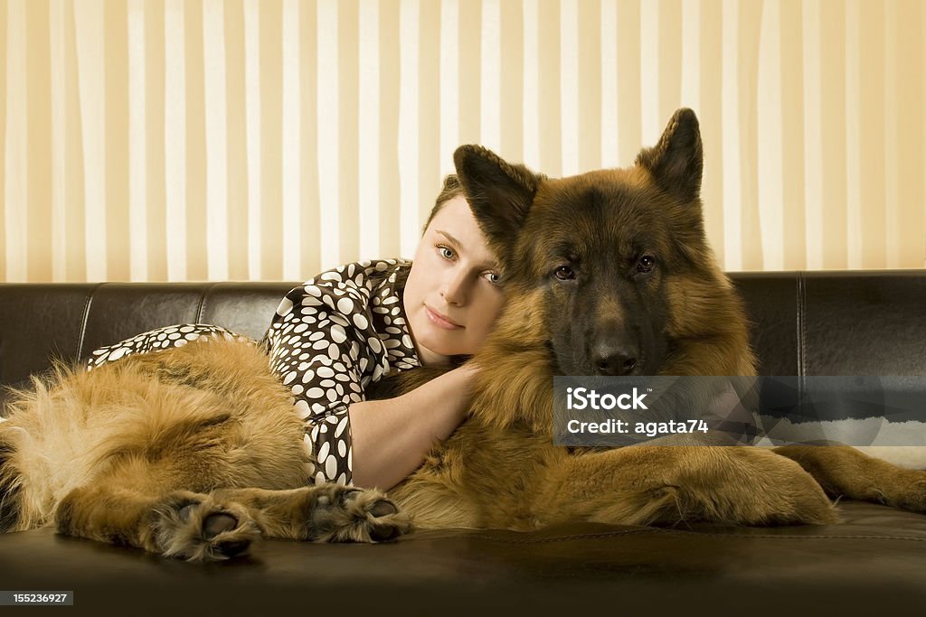 Woman and her dog laying on a sofa Beautiful girl and her dog breed German shepherd lying on the leather sofa Adult Stock Photo