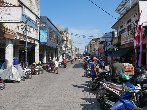 July 10, 2023 - Bandung, West Java, Indonesia.
View of Jl. Cibadak in downtown Bandung City with a paved road, parked motorbikes and cars and people on the street. Jl. Cibadak is famous for wholesale shops selling all kinds of products.