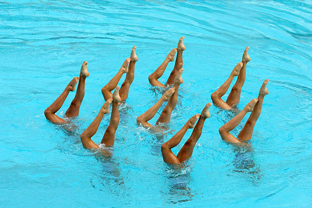 Synchronized Swimming Synchronized Swimmers legs point up out of the water in action co ordination stock pictures, royalty-free photos & images