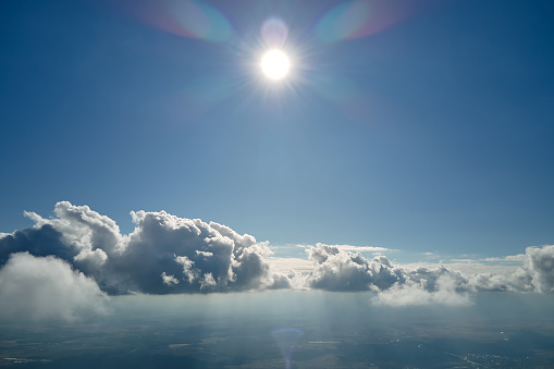 Aerial view from airplane window at high altitude of earth covered with white puffy cumulus clouds.