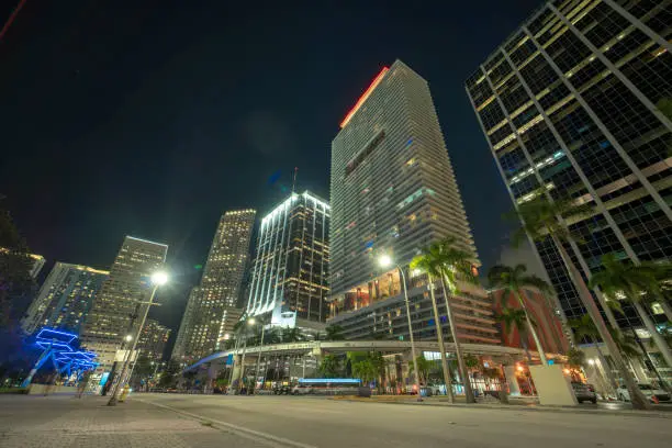 Downtown of Miami Brickell in Florida, USA. Brightly illuminated high skyscraper buildings and street with car trails and metrorail traffic in modern american midtown.