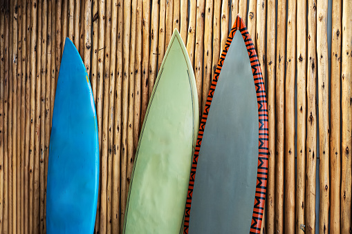 three worn surfboards against the wall made of bamboo.
