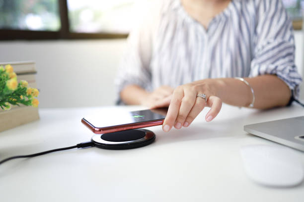 istock Charging mobile phone battery with wireless charging device in the table. Smartphone charging on a charging pad 1552445913