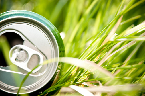 opened green aluminum can (bottle) laying in green grass