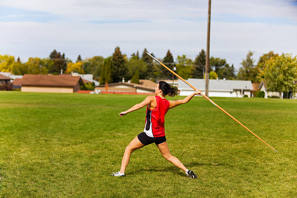 Javelin Throwing A young, female athlete throwing a javelin in a track and field event. spear stock pictures, royalty-free photos & images