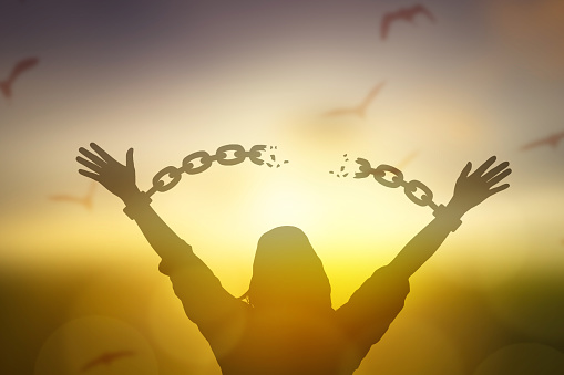 silhouette women hand up and broken chain and bird sunrise background .freedom concept