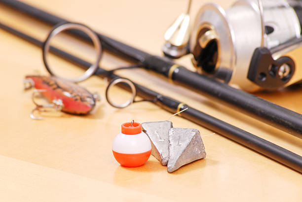 Fishing Weights and Floater Next to Black Fishing Rod on table