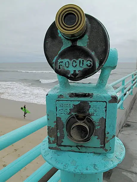 View of Pacific ocean from Manhattan Beach Pier, California. Old pay telescope in foreground, surfer in background  