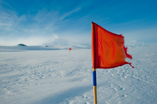 A red flag blows in the wind on the McMurdo Sound Ice Shelf with Mt Erebus, Ross Island in the Background.