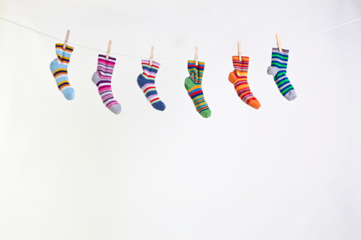 six different color socks hang on rope grafted with clothespin