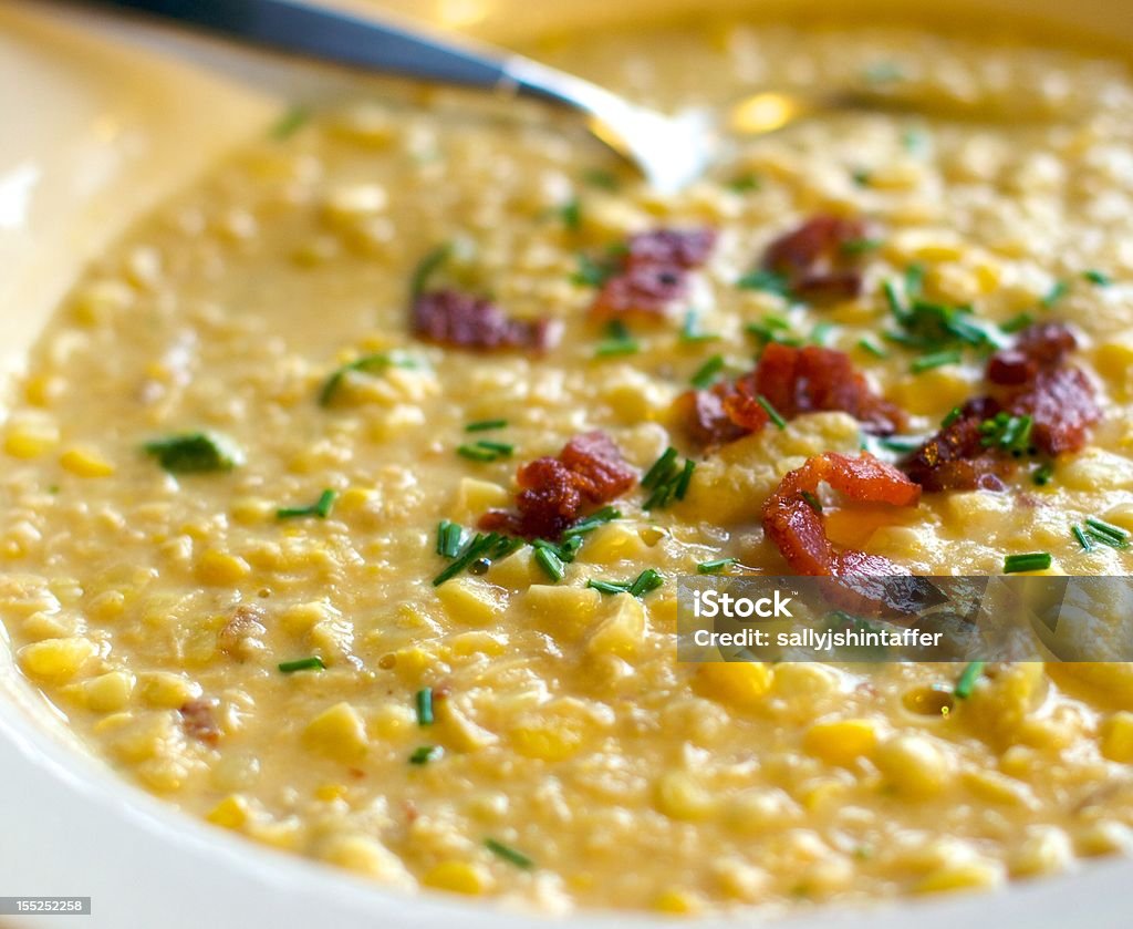 Bowl of Corn Chowder Corn chowder in a white bowl with a spoon, garnished with crisp bacon and chives.   Corn Chowder Stock Photo