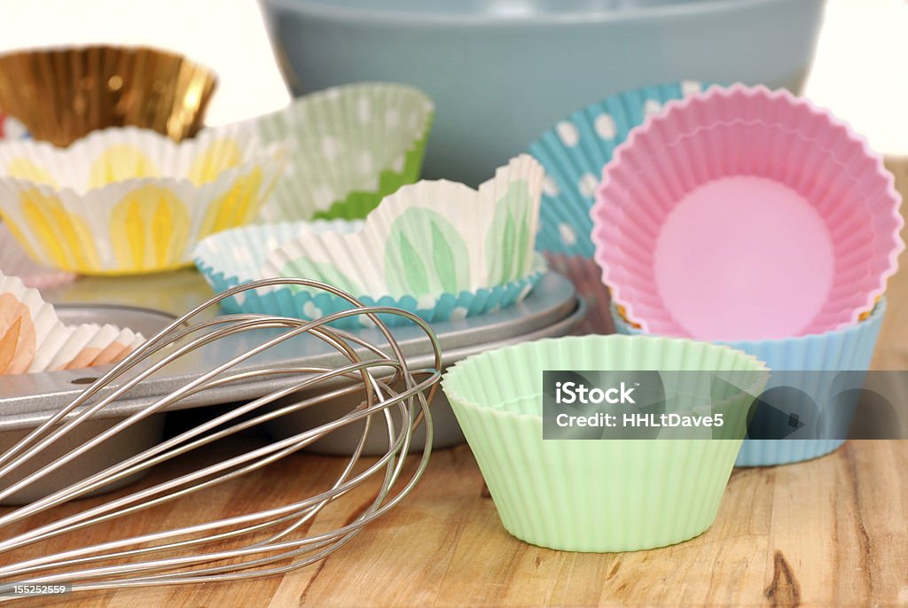 Variety of cupcake liners with wire wisk Variety of cupcake liners in different colors with a muffin pan and wire wisk Cupcake Holder Stock Photo