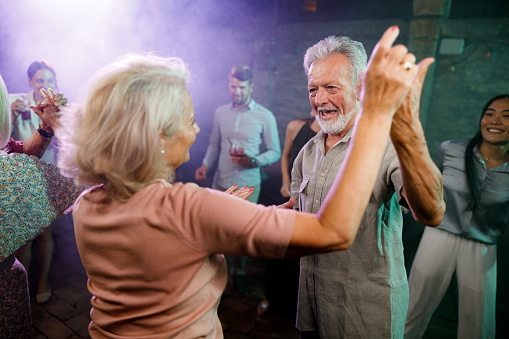Happy senior couple having fun while dancing during nightlife in a disco.