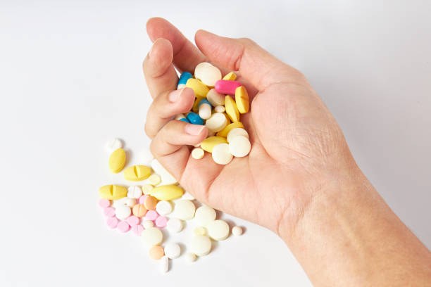 Hand holding A lot of pills different colors (white, pink, orange and blue color) and shapes on a white background. Antipyretics, painkillers and antibiotics. Take medicine overdose. kill oneself. Hand holding A lot of pills different colors (white, pink, orange and blue color) and shapes on a white background. Antipyretics, painkillers and antibiotics. Take medicine overdose. kill oneself. harakiri photos stock pictures, royalty-free photos & images