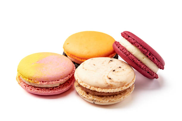istock Close up of 4 colorful macarons (pink, red, orange and cream-brown) isolated on white background. 1552564828