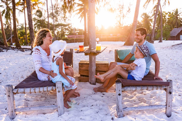 istock Happy family talking on deck chairs at the beach. 1552566356