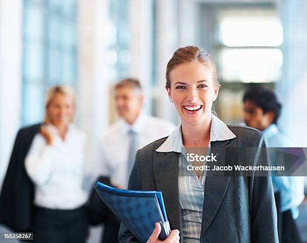 Foto de Feliz Mulher De Negócios Com Os Colegas No Fundo e mais fotos de stock de 20 Anos - 20 Anos, 20-24 Anos, Adulto