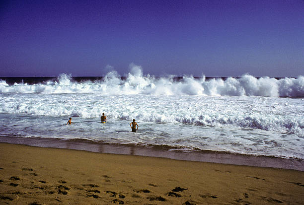Playing in the waves, circa 1980 A few young adults playing in the waves at Newport Beach in Southern California. hearkencreative stock pictures, royalty-free photos & images
