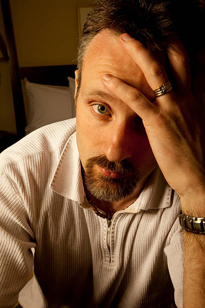 istock depressed man in hotel room holding head 155258647