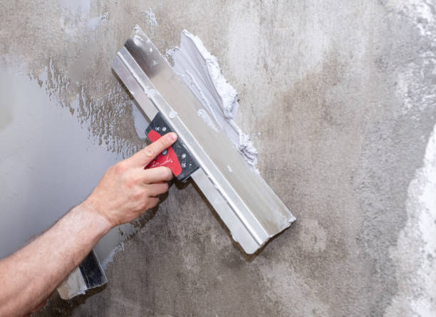 istock Close-up of a man's hand, a master builder applies putty on a plastered wall. Puttying with a construction spatula. 1552602323