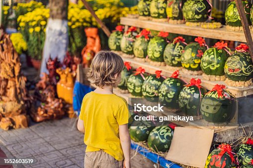istock Boy tourist look at Watermelons with festive engraving on Tet Eve. Tet is Lunar New Year and celebrated during four days in Vietnam 1552603519