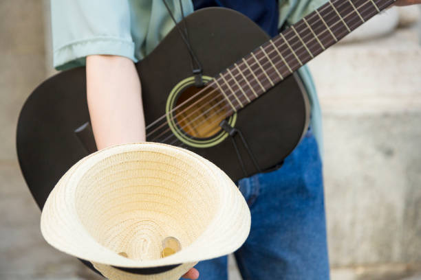 Close-up Detail of Street Musician's Hat Adorned with Collected Coins from Passersby.