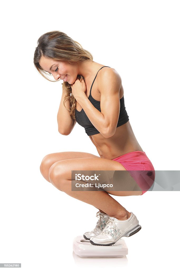 Woman who lost weight standing on a tiny scale Girl standing on a scale isolated on white background Looking Stock Photo