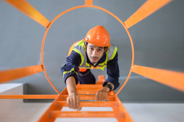 istock High angle look down view over young Asian technician worker climbing ladder for inspect or maintenance machine in high voltage electric transformer sub station. Industrial business occupation worker concept. 1552633003